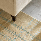 Whipstitch Stickley wool rug in tan with a green and blue bamboo silk plaid pattern under a chair leg