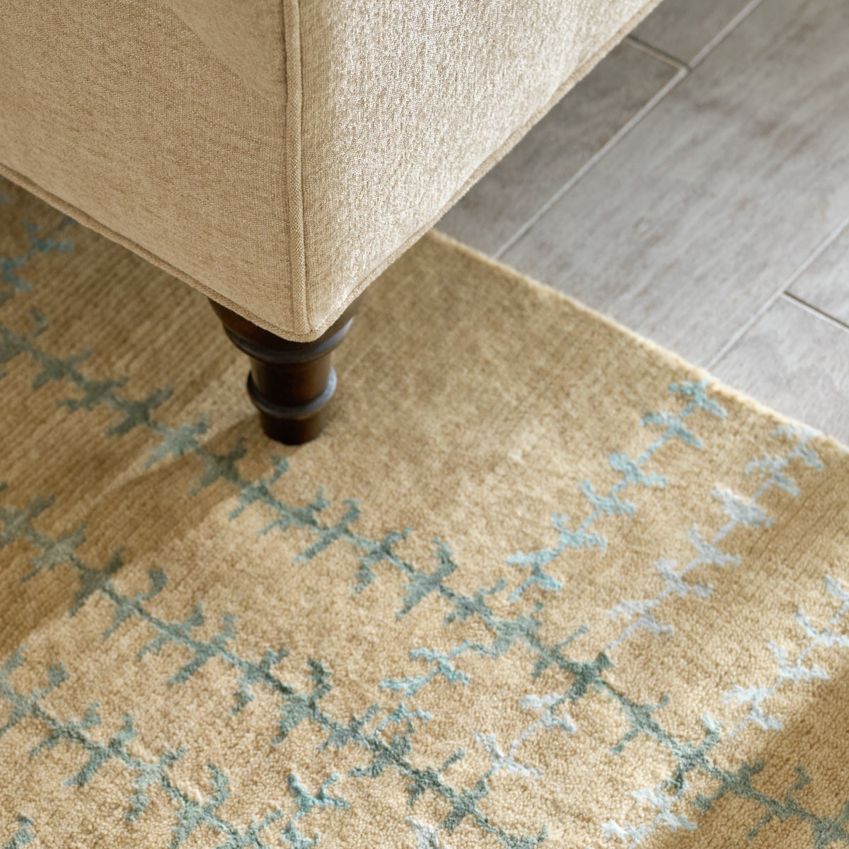 Whipstitch Stickley wool rug in tan with a green and blue bamboo silk plaid pattern under a chair leg