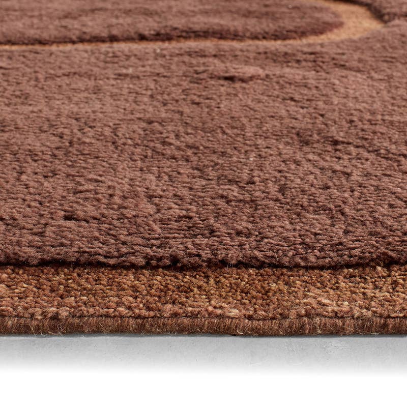 Close-up of the brown Solum hand-woven wool rug showing its thick, textured pile and layered design.