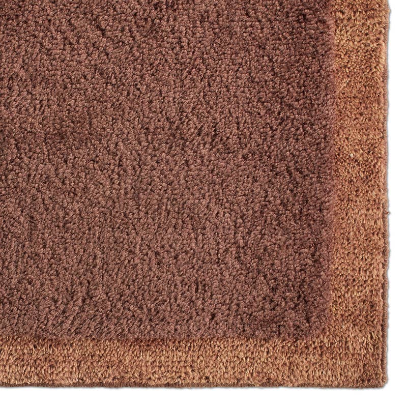 Solum hand-woven wool rug corner in brown and tan with a thick, textured pile.