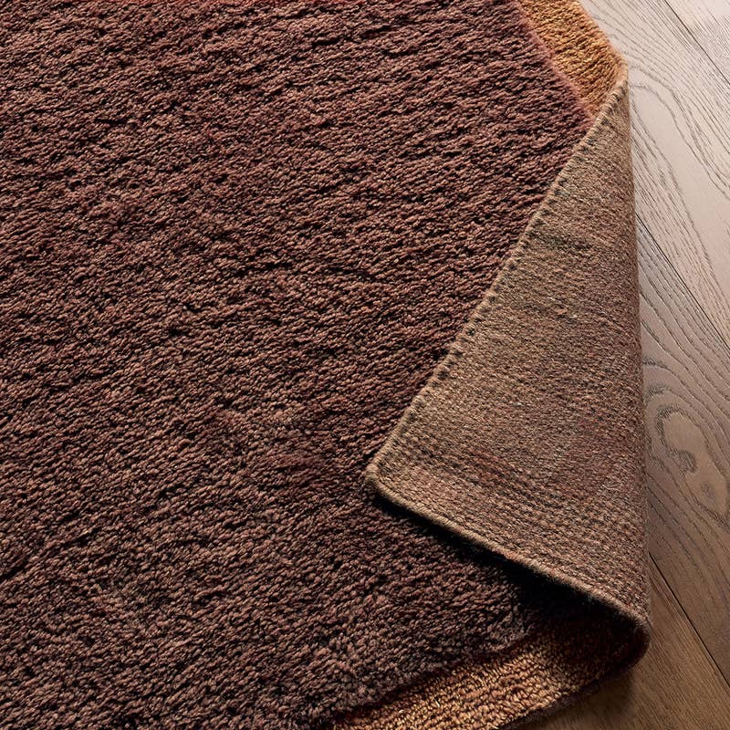 Solum brown hand-woven wool rug with a thick, textured pile on a wood floor.