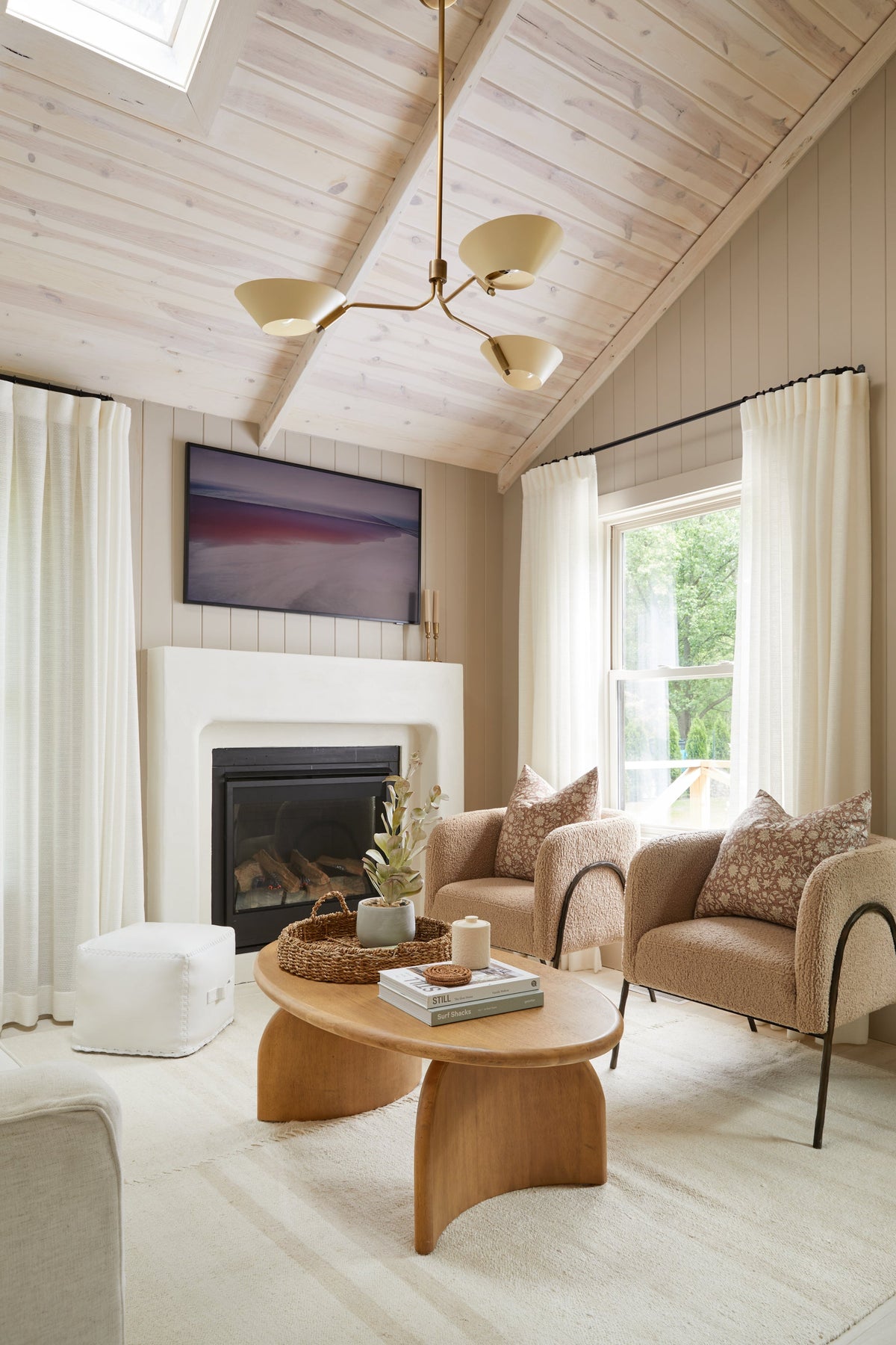 Sacramento brass chandelier with sweeping arms in a modern, neutral living room.