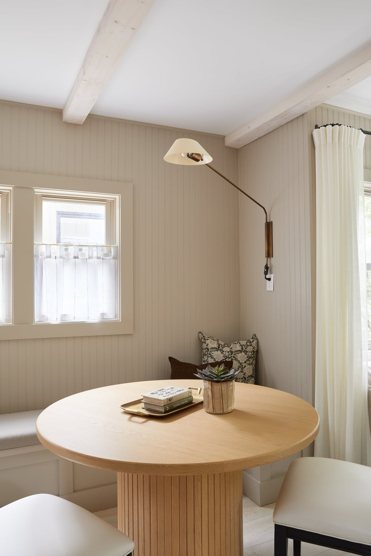 Sacramento brass plug-in sconce with a soft sand shade mounted over a wooden dining table.