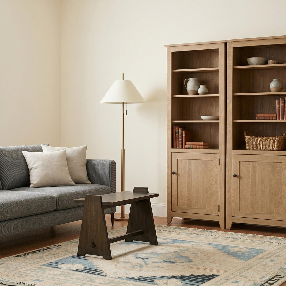 Two light wood Shaker bookcases with shelves and lower cabinets in a living room.