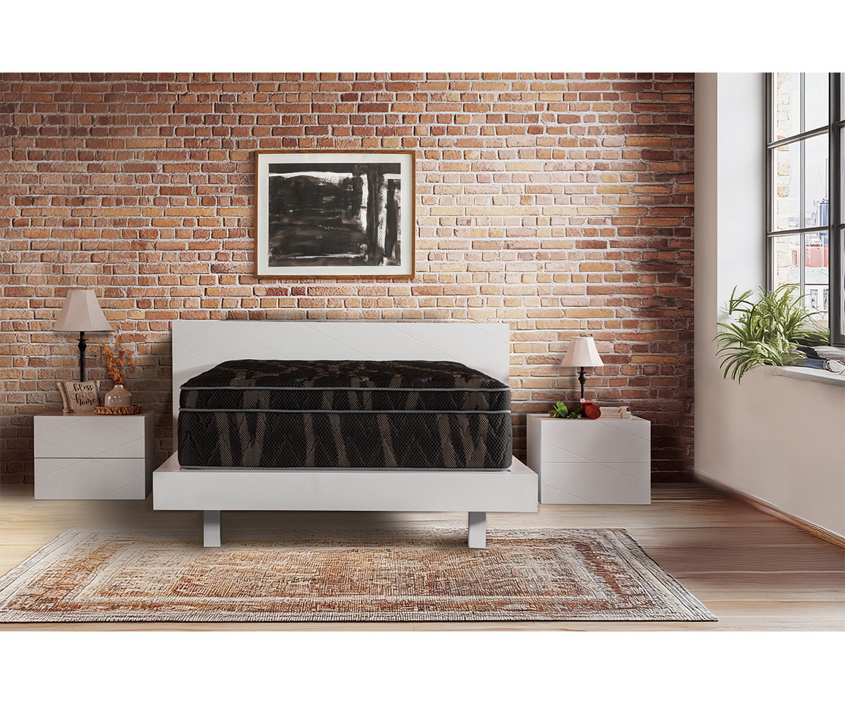 Astra Luxe Euro-top mattress in dark grey on a white bed frame against a brick wall.