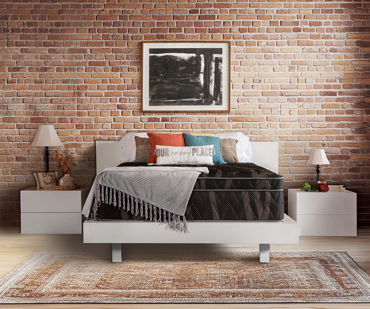 Astra Luxe Euro-top mattress on a white bed frame against a brick wall.