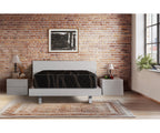 Lumina medium-firm mattress on a white bed frame in a brick-walled bedroom.