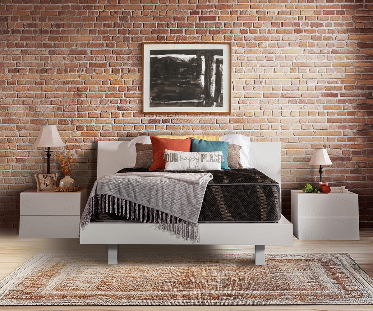 Lumina medium-firm mattress on a white bed frame against a brick wall.