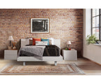 Lumina medium-firm mattress on a white bed frame in a brick-walled bedroom.
