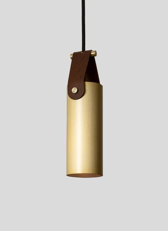 Spero Pendant light with a cylindrical brass body and brown leather strap.