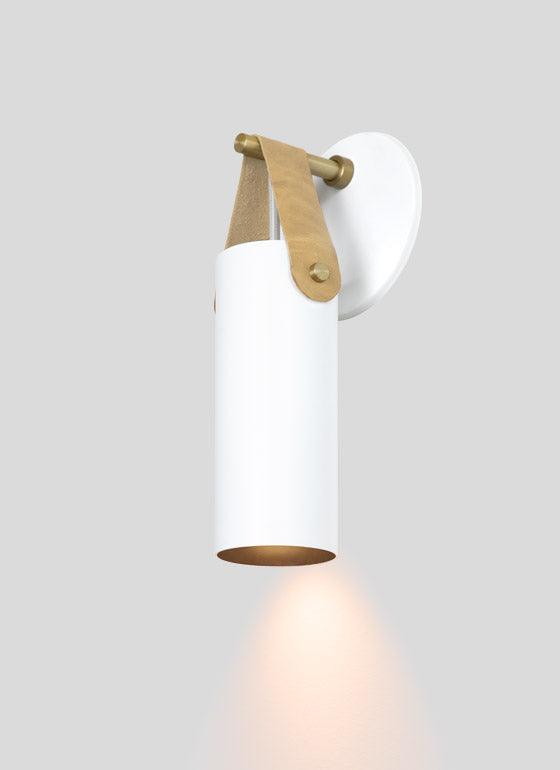 Spero minimalist white cylinder wall sconce with brass and tan leather strap hanging detail.
