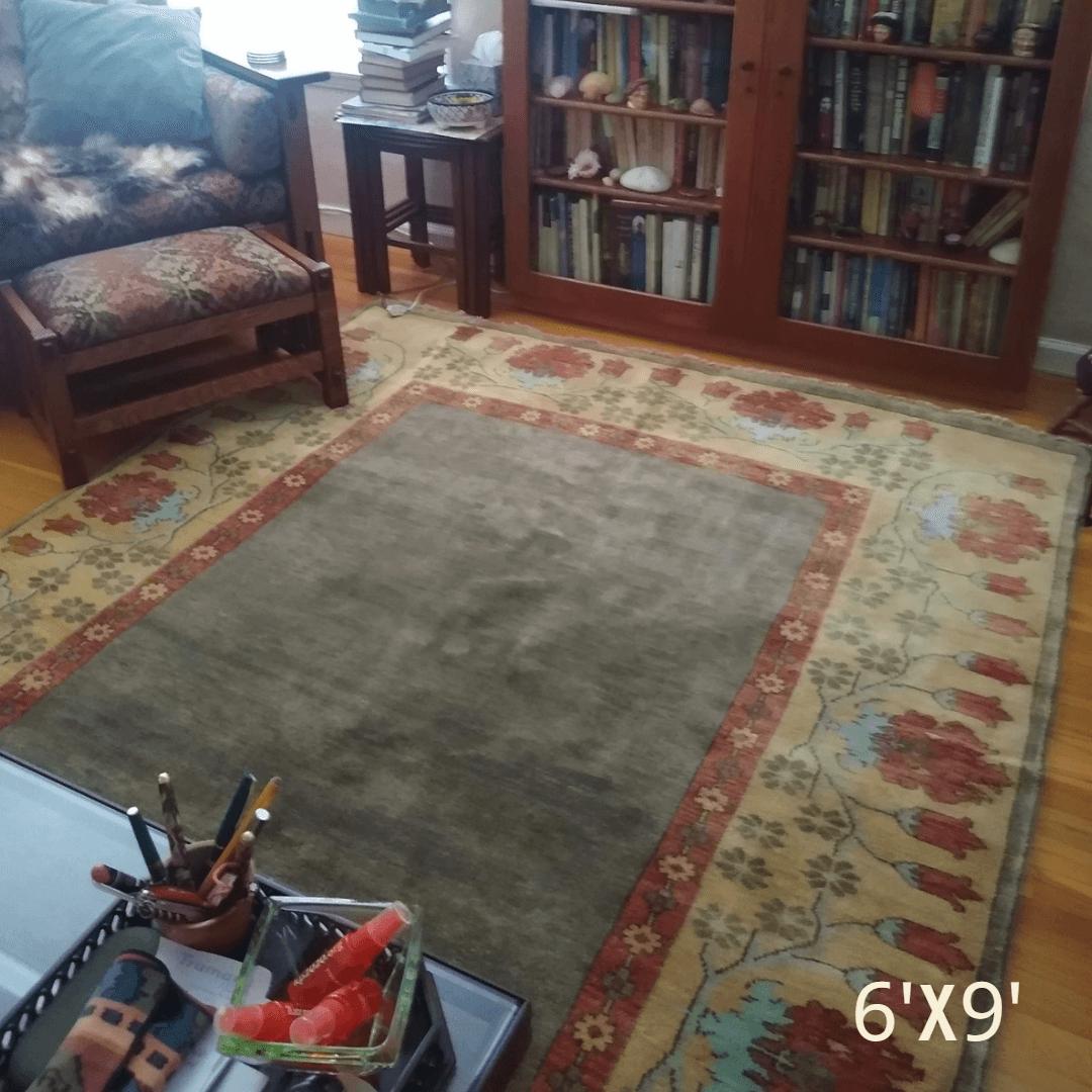 Streatham Border 6'x9' hand-knotted wool rug with brown center and floral border in a living room.