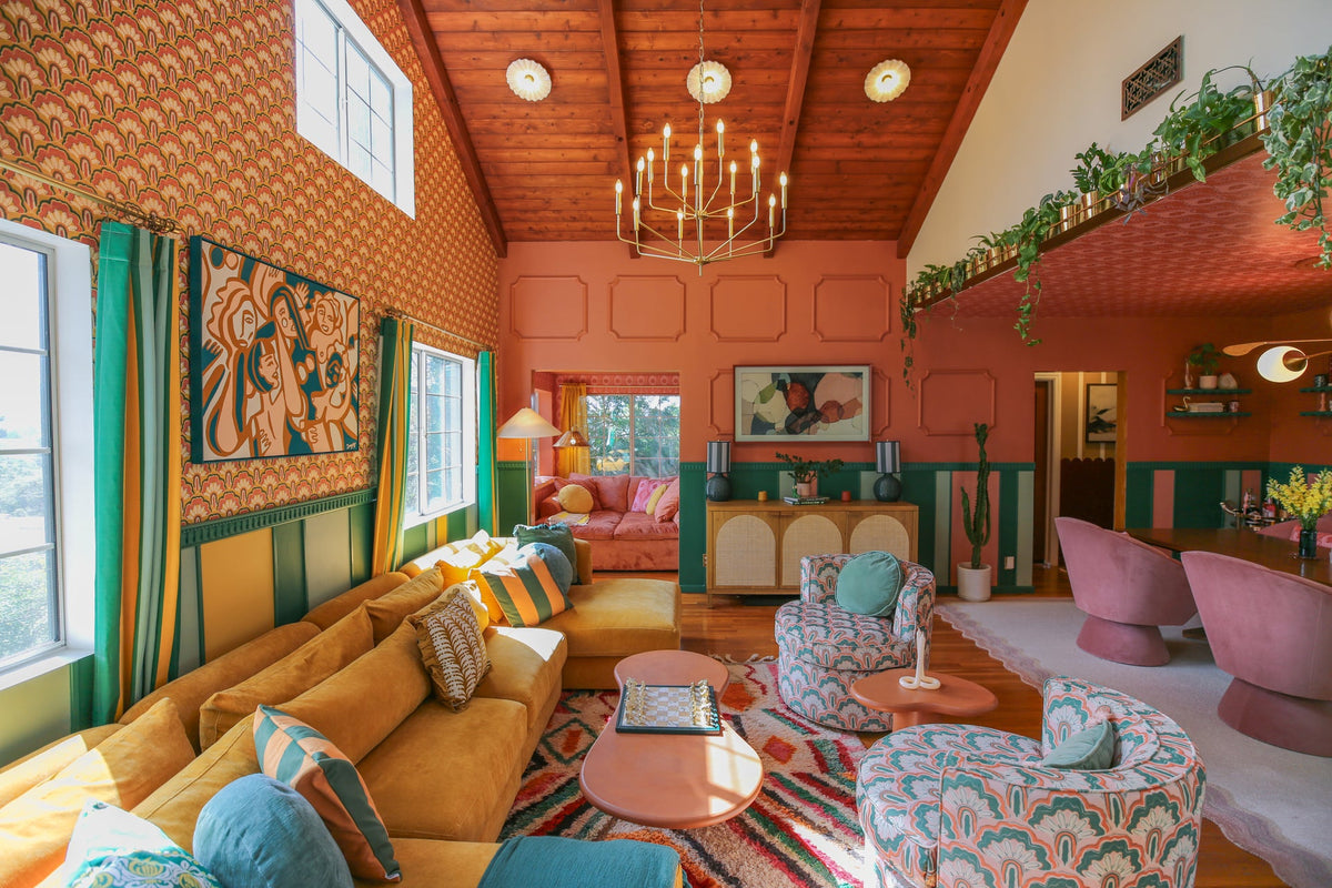 Colorful maximalist living room with a yellow sectional, patterned armchairs, and a wood ceiling.