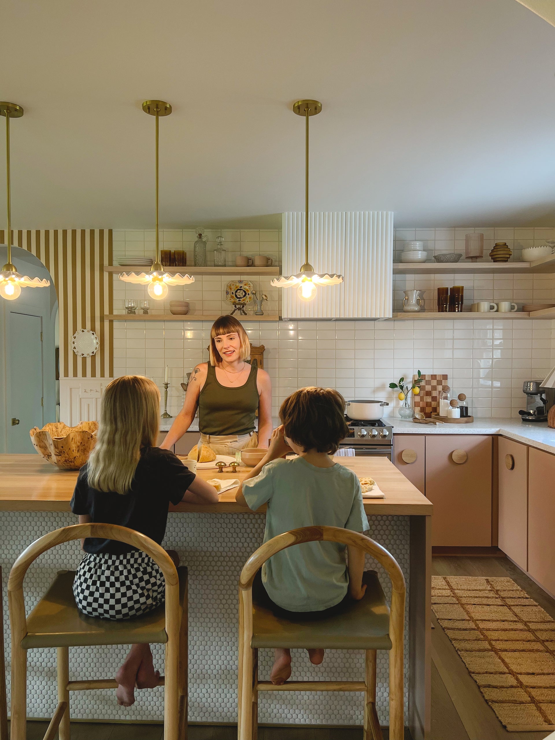 Tinsley Pendant lights with white ceramic collars and brass pipes over a kitchen island.