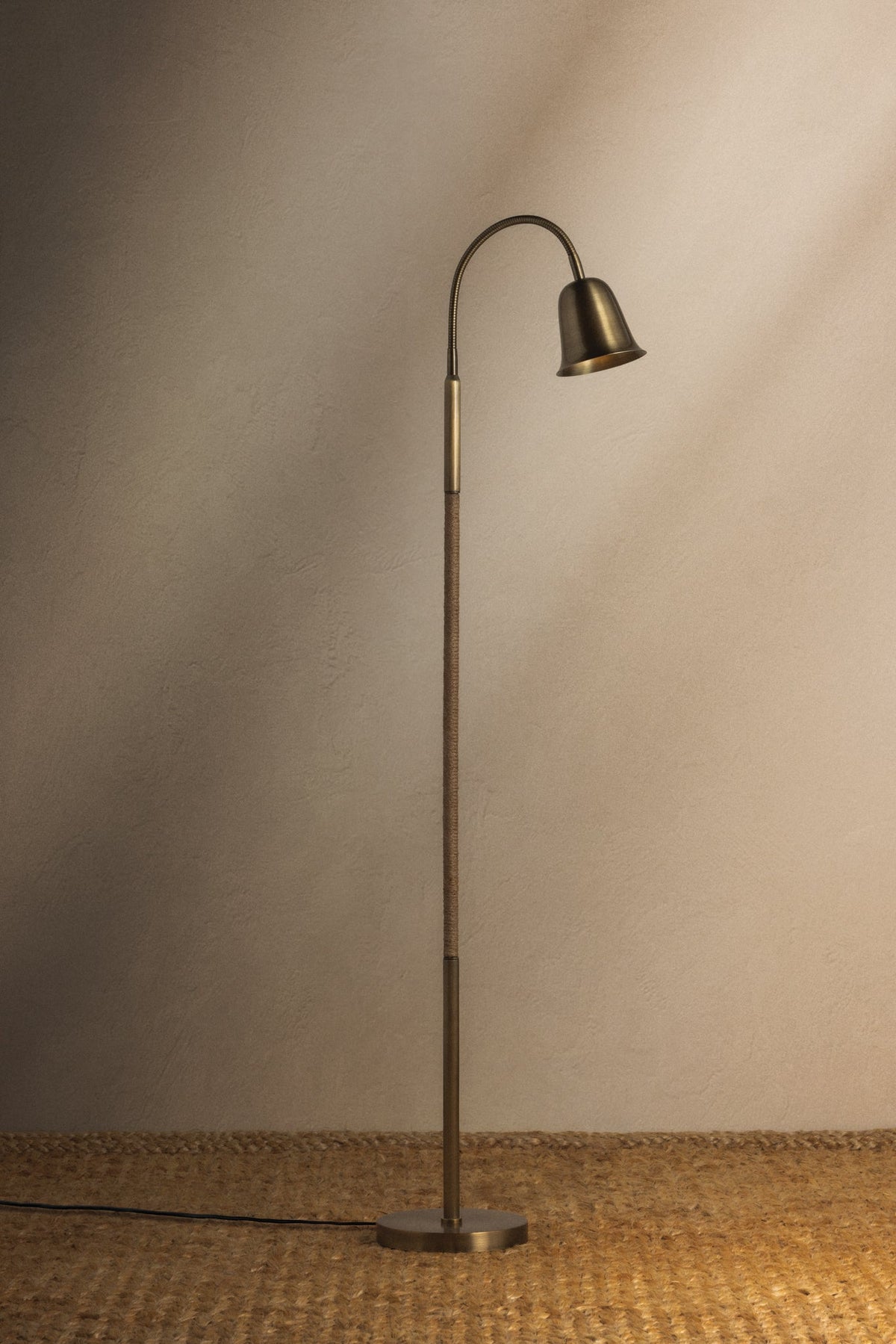 Wharf floor lamp in patina brass with a jute-wrapped stem and adjustable gooseneck.