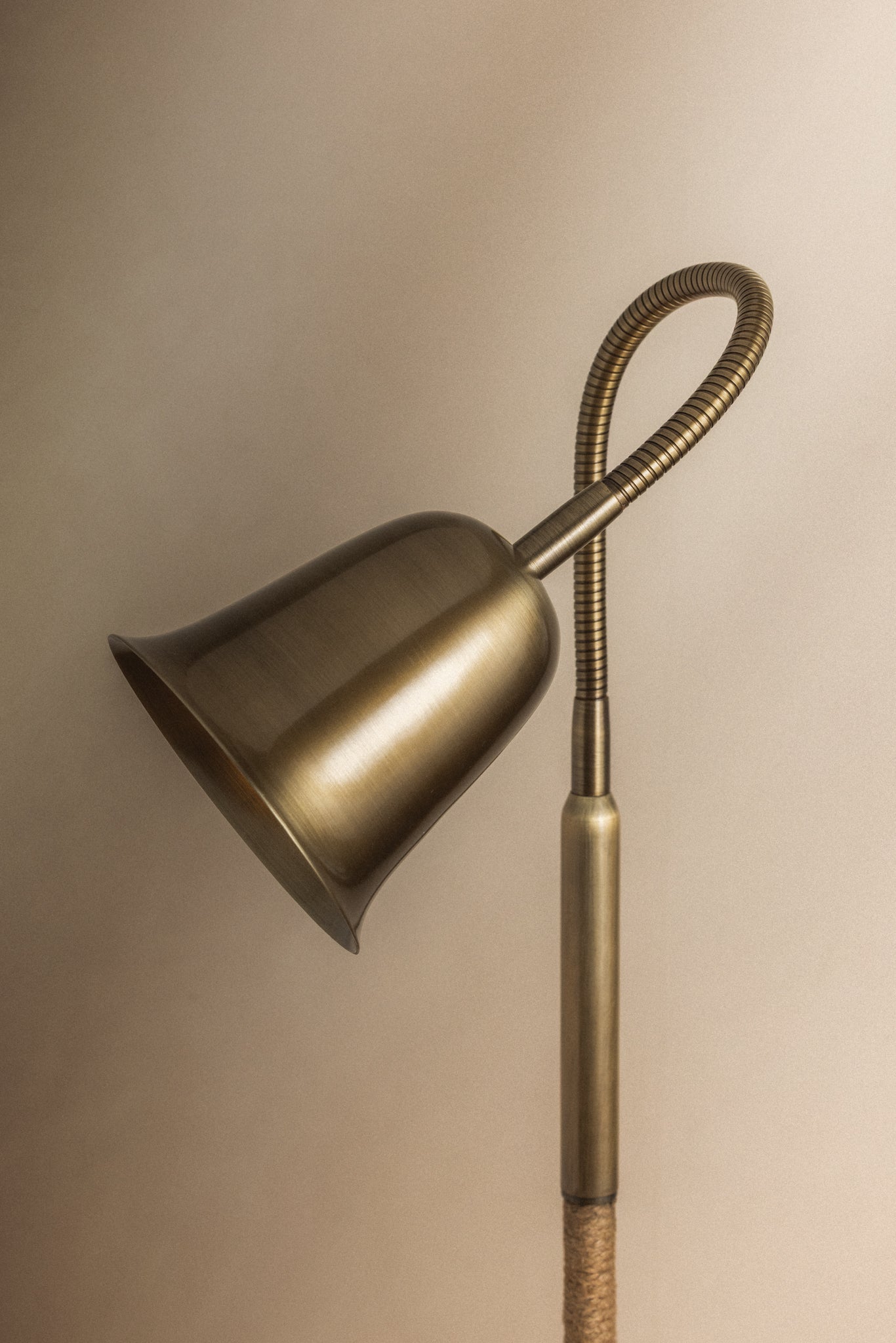 Wharf floor lamp in patina brass with a bell-shaped shade, adjustable gooseneck, and jute-wrapped pole.