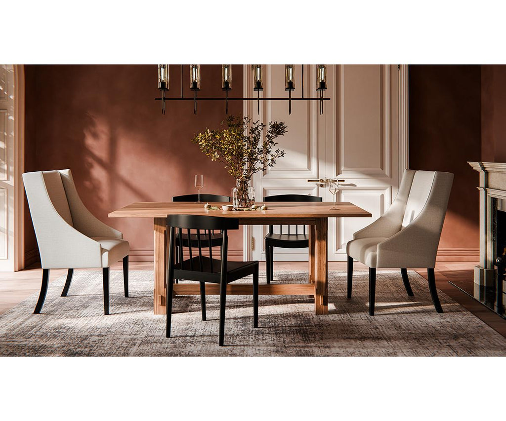 Magnolia wooden trestle dining table with black and beige chairs on a textured rug