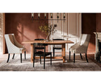 Magnolia wooden trestle dining table with black and beige chairs on a textured rug
