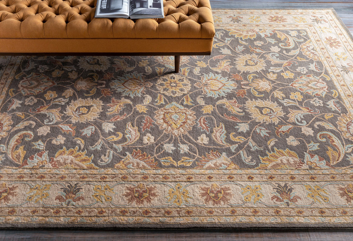 Nobility Flint hand-tufted wool rug with a charcoal floral pattern and mustard accents under a tufted bench.