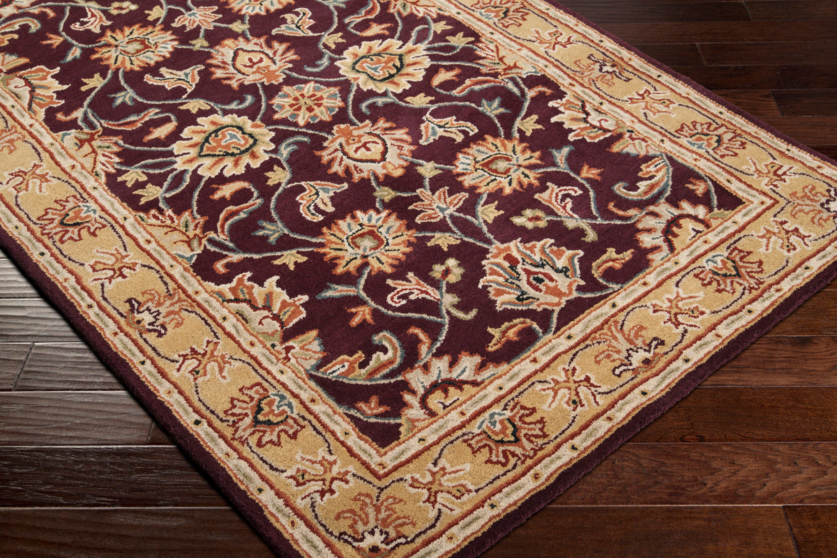 Nobility Amethyst hand-tufted wool rug with burgundy floral pattern and tan borders on dark wood floor.