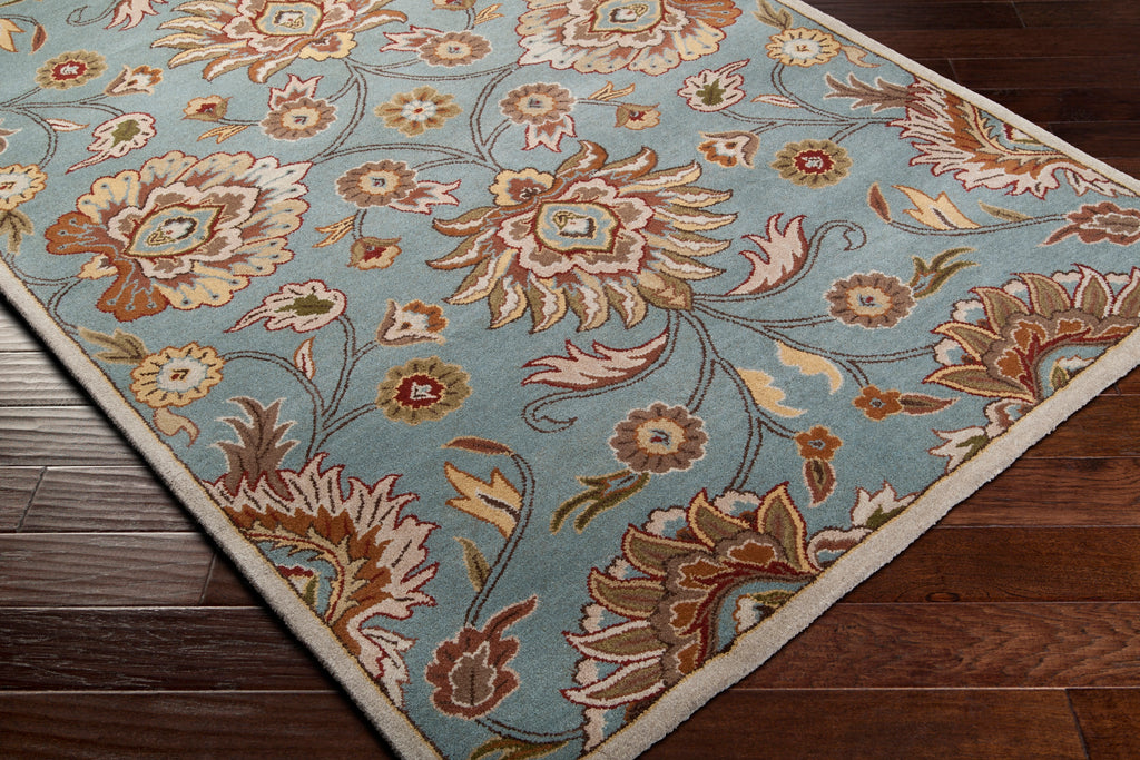 Mediterranean Cerulean hand-tufted wool rug with a classic floral pattern on dark wood floors.