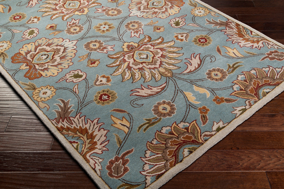 Mediterranean Cerulean hand-tufted wool rug with a classic floral pattern on dark wood floors.