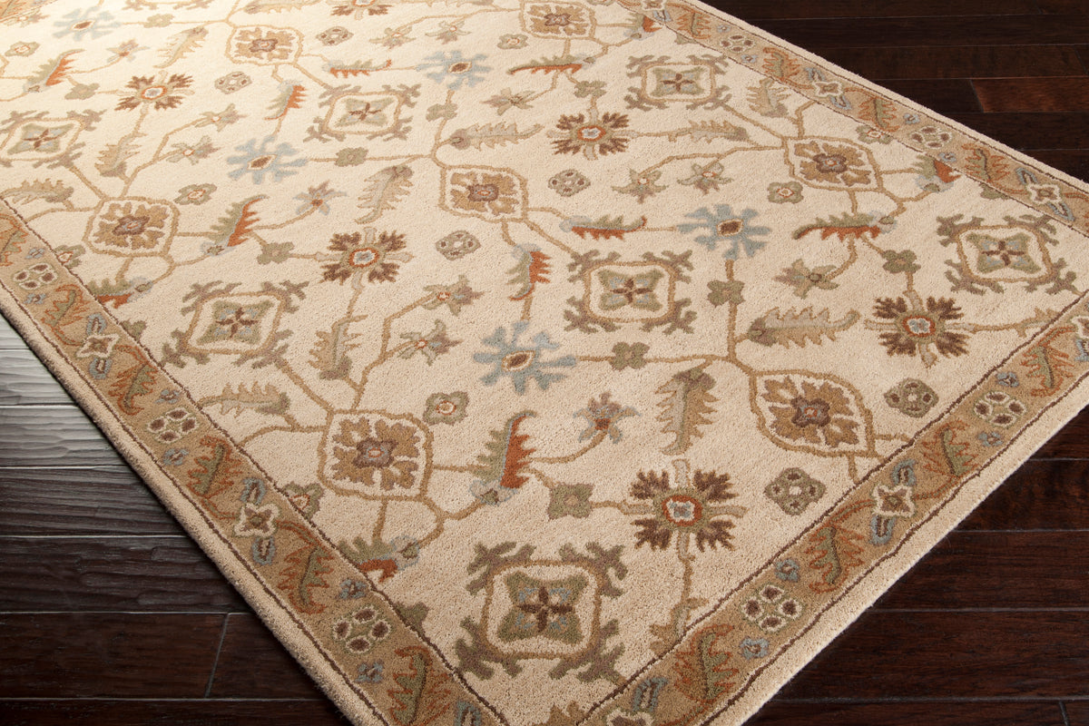 Carthage Beige hand-tufted wool rug with traditional floral patterns on dark wood floor.