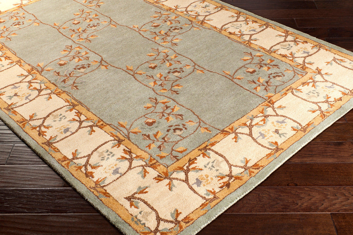 Corinth Azure hand-tufted wool rug with light blue backdrop and floral border on dark wood floor