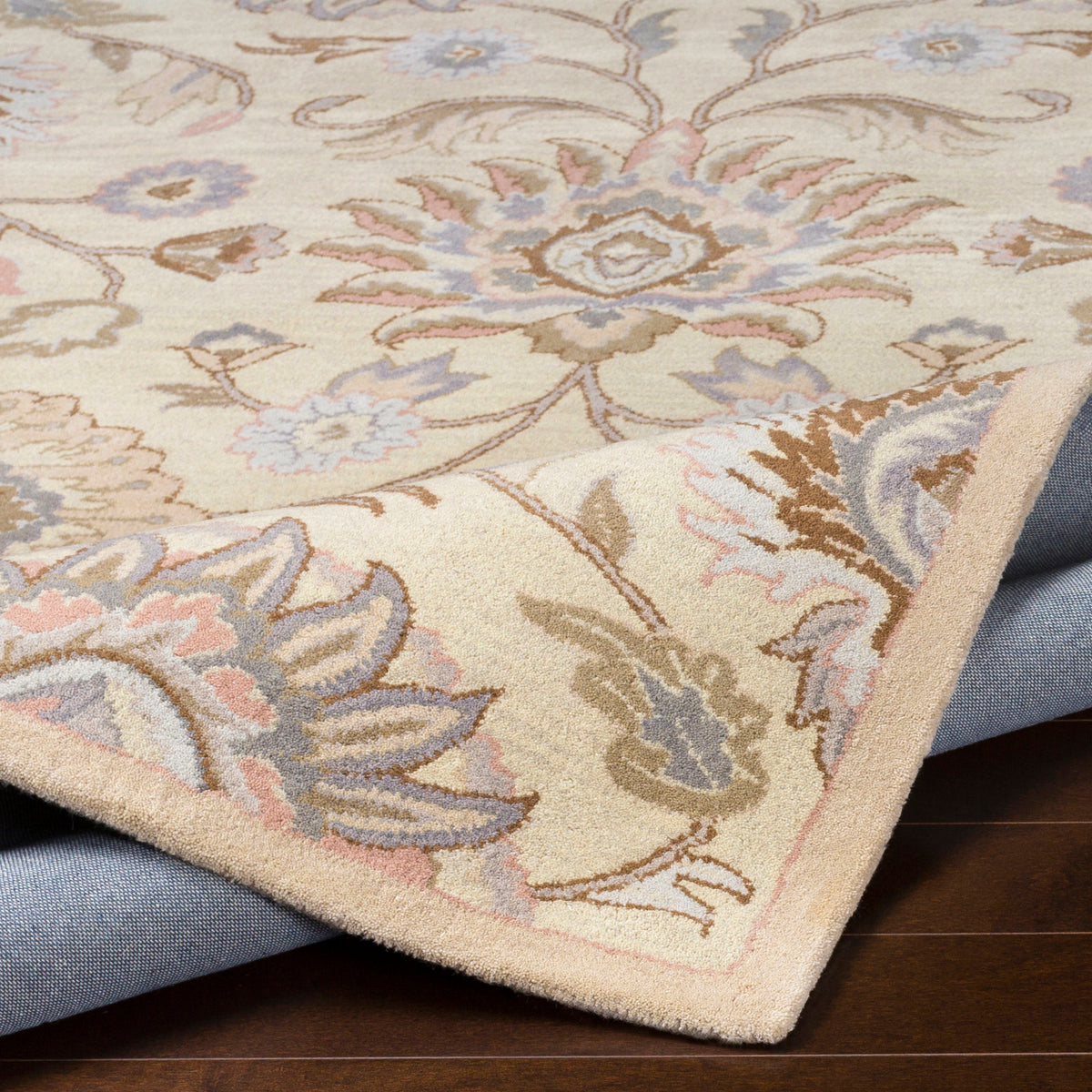 Mediterranean Lilac hand-tufted wool rug with floral patterns and a folded corner showing the backing.