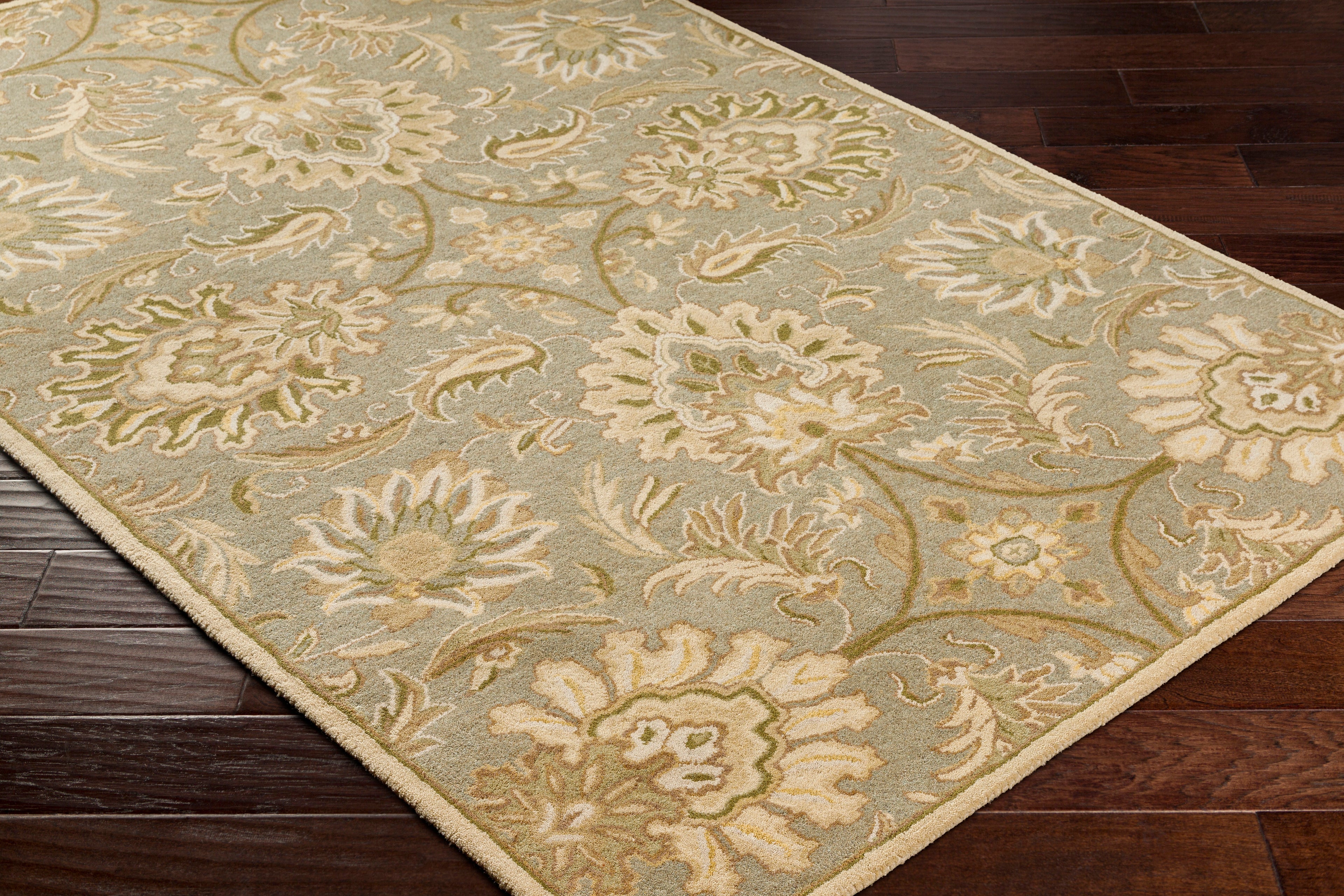 Mediterranean Sky hand-tufted wool rug with sage, ivory, and olive floral patterns on dark wood floor.