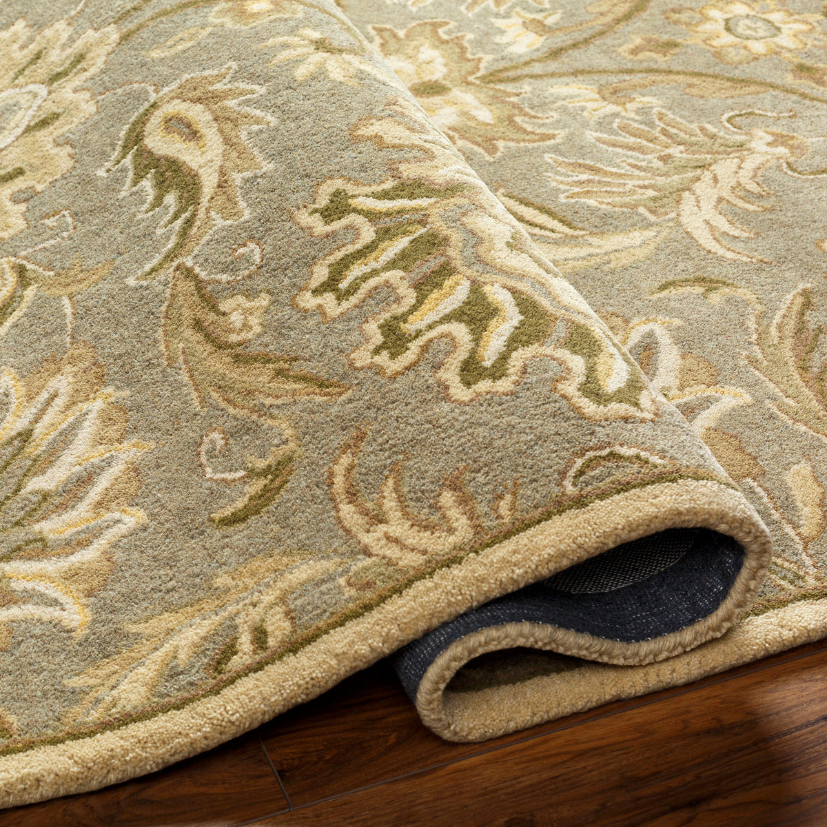 Mediterranean Sky hand-tufted wool rug with sage, olive, and ivory floral patterns on wood floor.