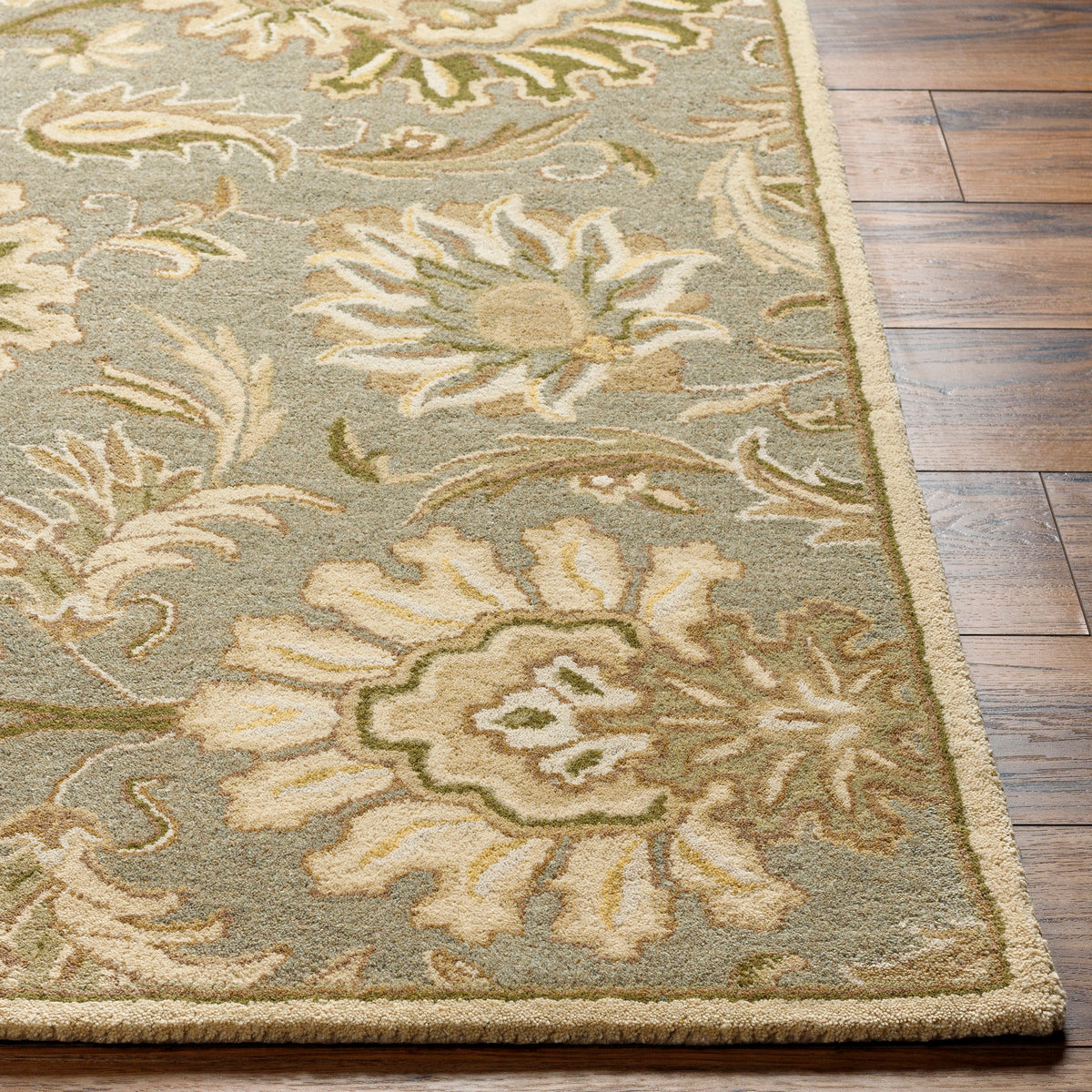 Mediterranean Sky hand-tufted wool rug with sage, ivory, and olive floral patterns on hardwood floor.
