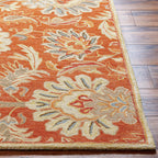 Mediterranean Cider hand-tufted wool rug with burnt orange floral patterns on wood floor