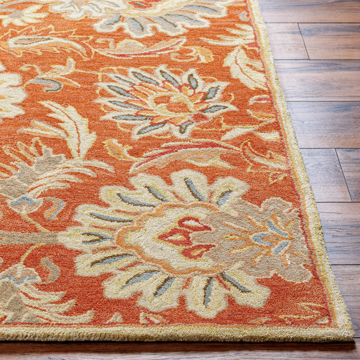 Mediterranean Cider hand-tufted wool rug with burnt orange floral patterns on wood floor