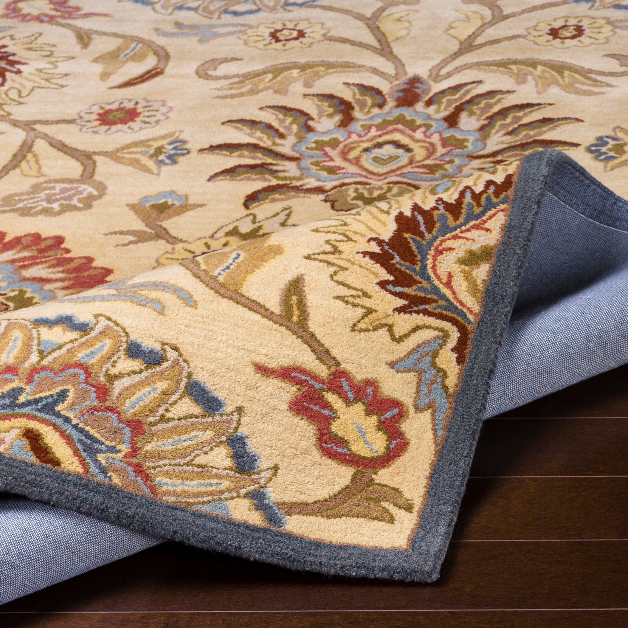 Mediterranean multi hand-tufted wool rug with floral patterns in red, blue, and tan.
