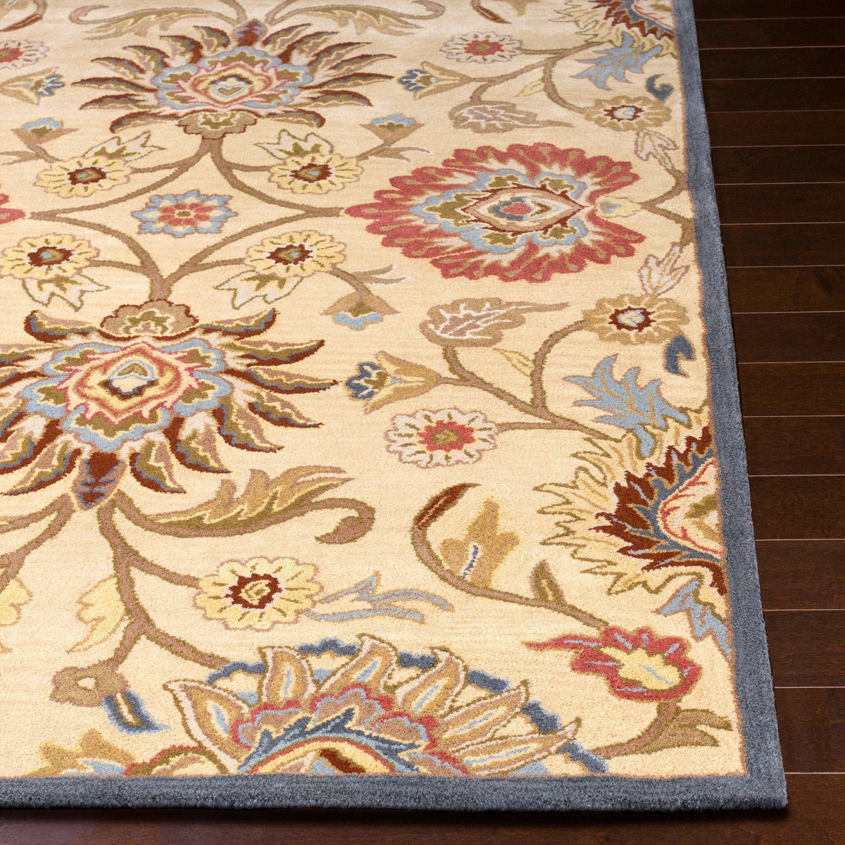 Mediterranean multi hand-tufted wool rug with floral patterns in red, blue, and tan on dark wood floor.
