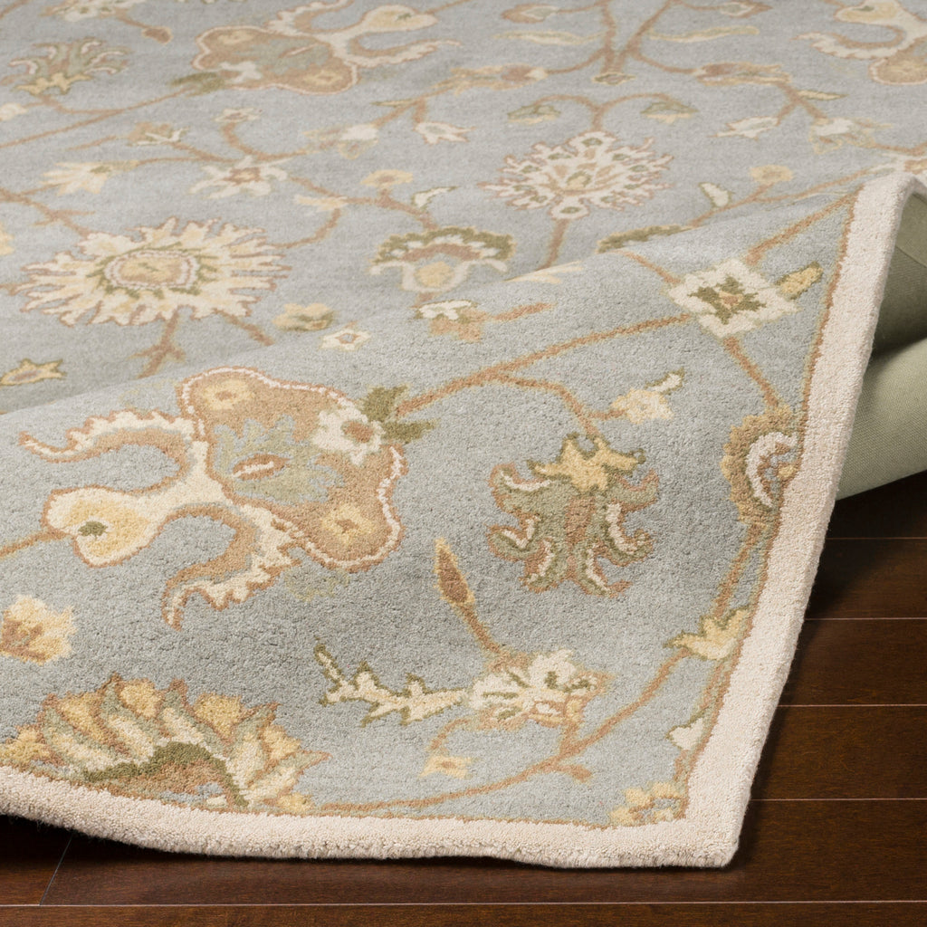 Giardino Stone hand-tufted wool rug with a blue-grey floral pattern on dark wood flooring.