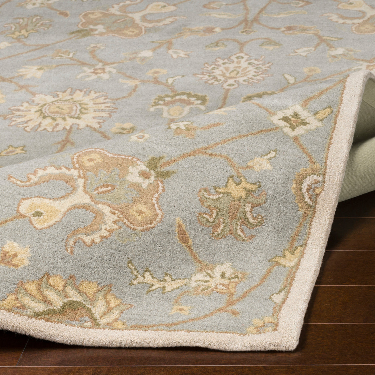 Giardino Stone hand-tufted wool rug with a blue-grey floral pattern on dark wood flooring.