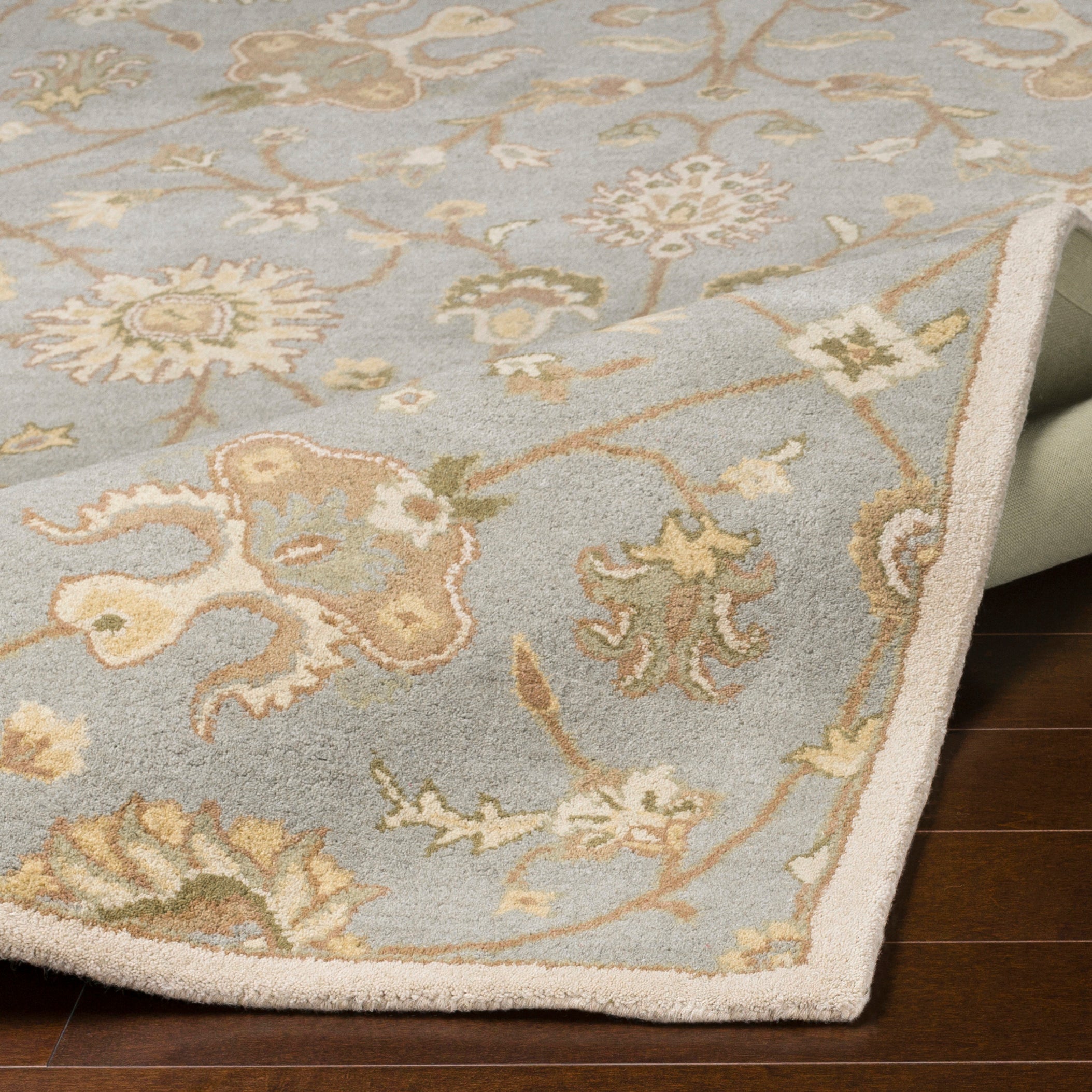 Giardino Stone hand-tufted wool rug with a blue-grey floral pattern on dark wood flooring.