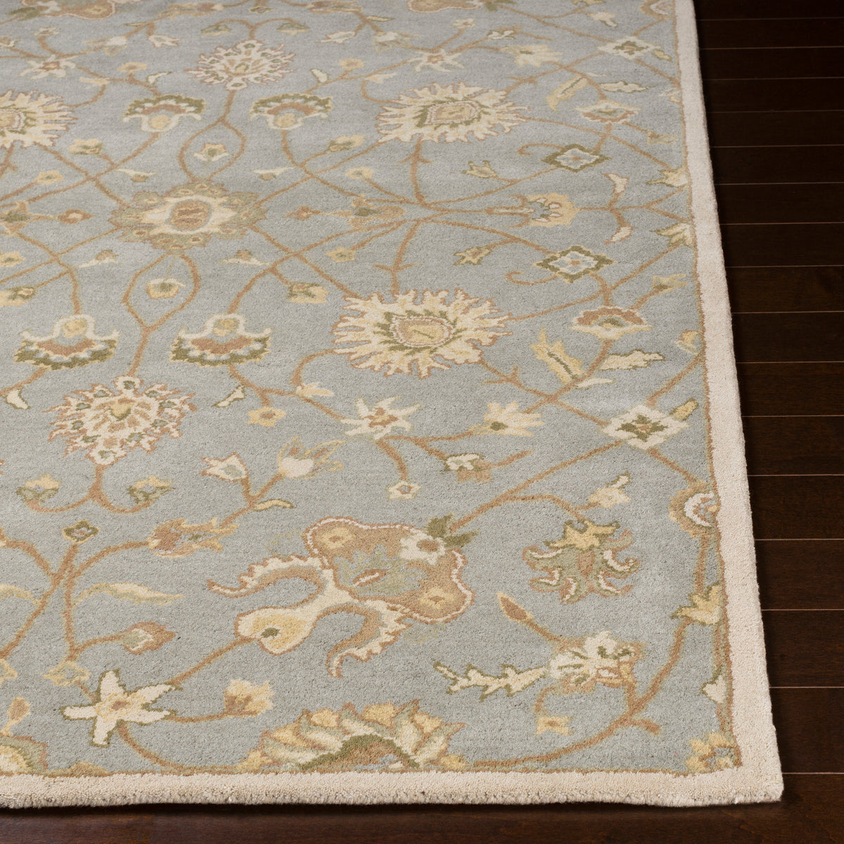 Giardino blue-grey hand-tufted wool rug with an elegant floral pattern on dark wood flooring.