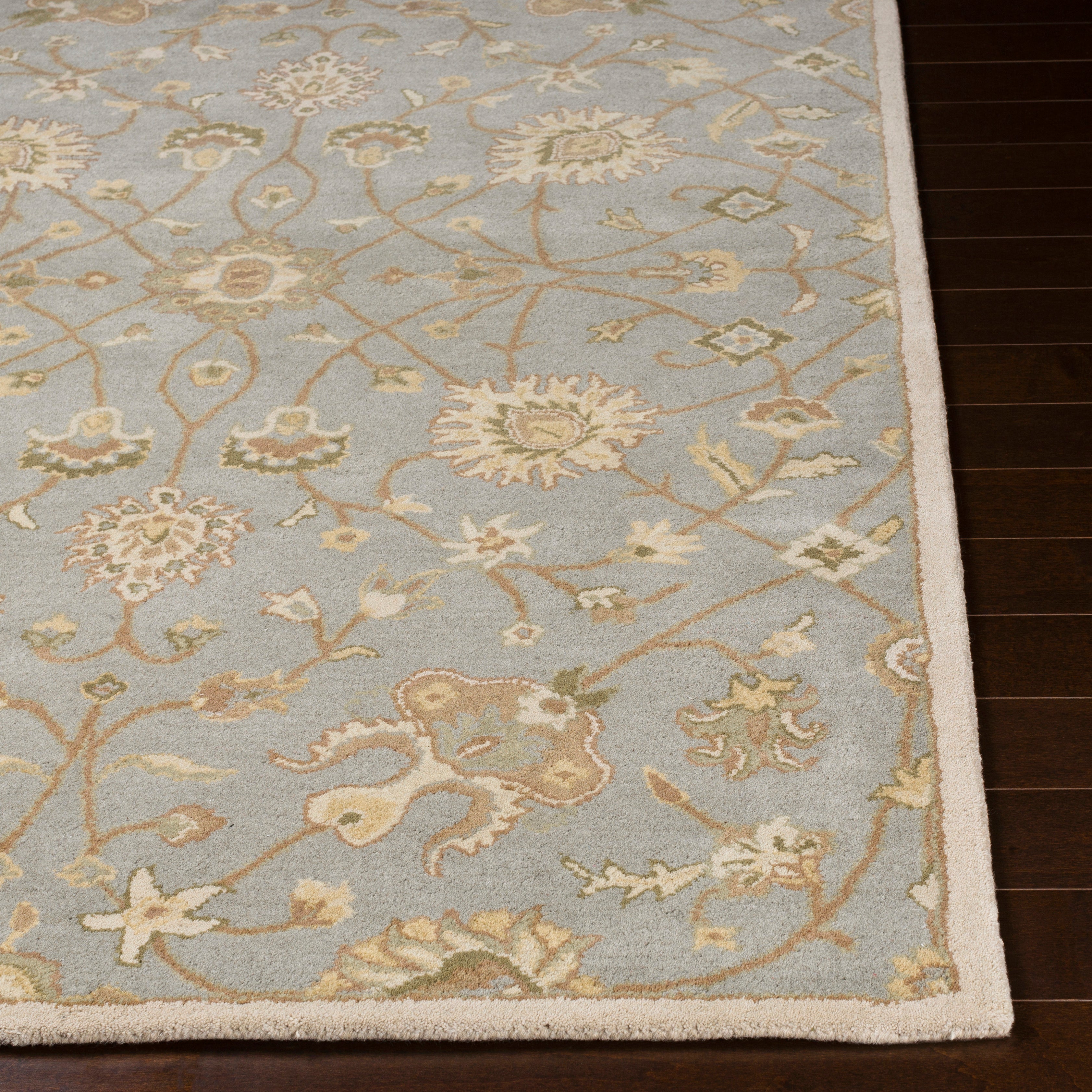 Giardino blue-grey hand-tufted wool rug with an elegant floral pattern on dark wood flooring.