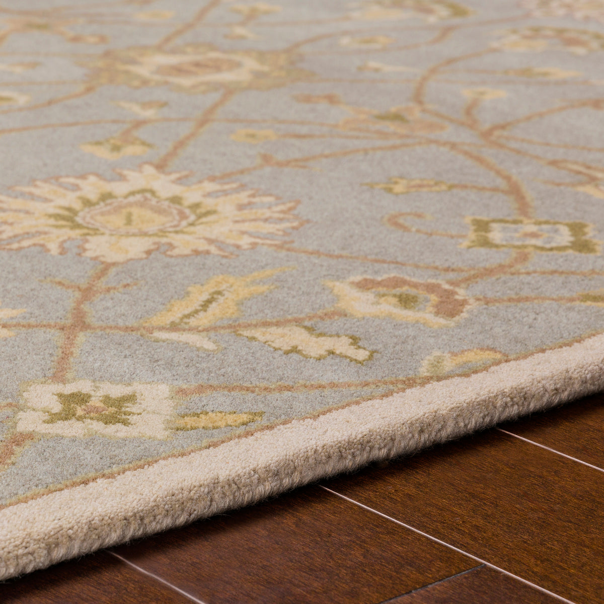 Giardino Stone hand-tufted wool rug with a blue-grey floral pattern on hardwood floor.