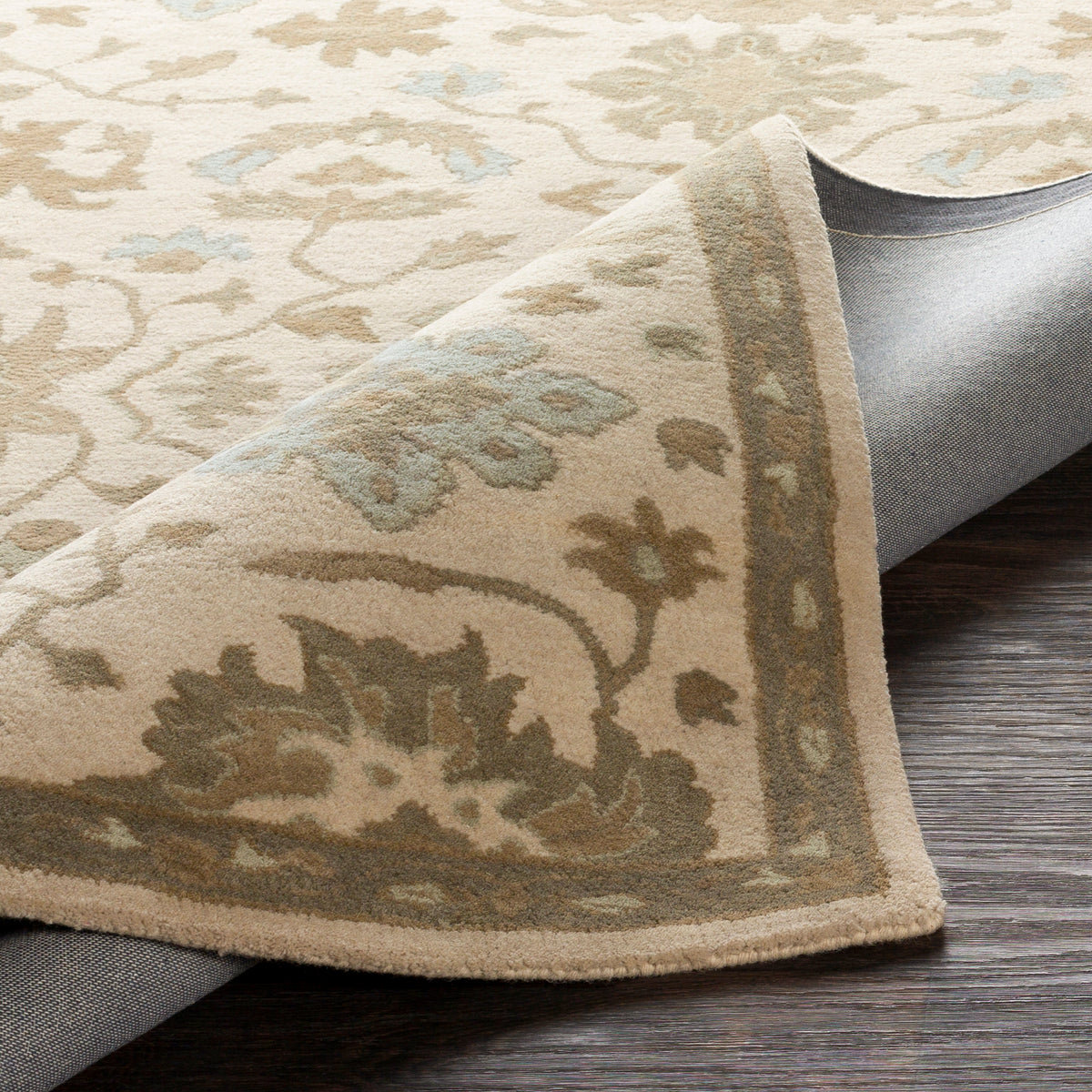 Julian Natural hand-tufted wool rug with a beige floral pattern, showing the corner folded back over a dark wood floor.