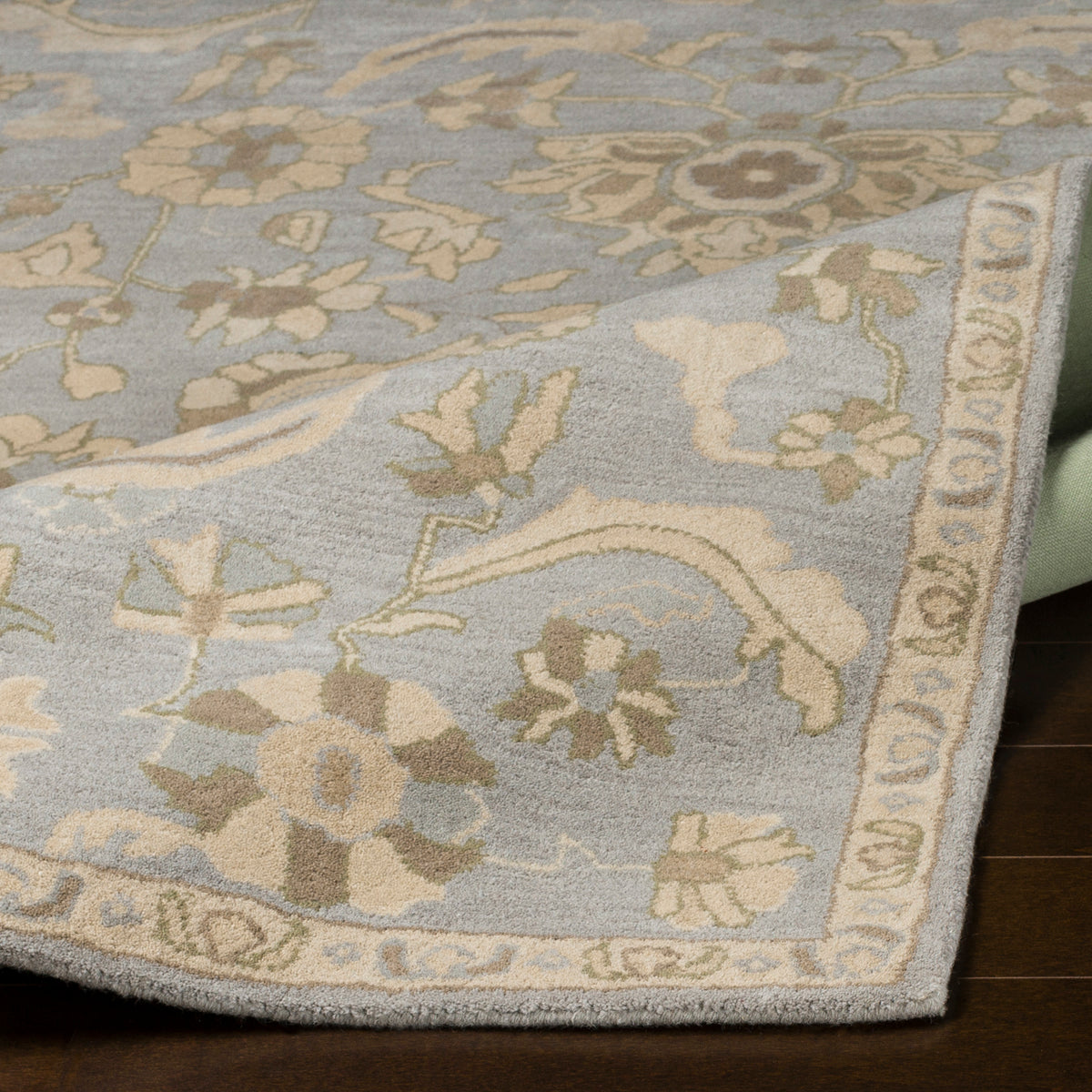 Julian Arctic hand-tufted wool rug in light blue with beige floral patterns.