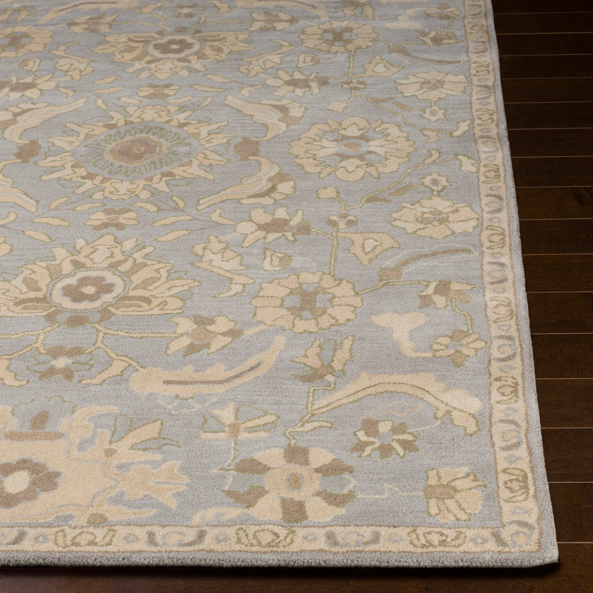 Julian Arctic hand-tufted wool rug with a light blue and beige floral pattern on dark wood flooring.
