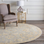 Julian Arctic round wool rug with a light blue and beige floral pattern under an armchair.