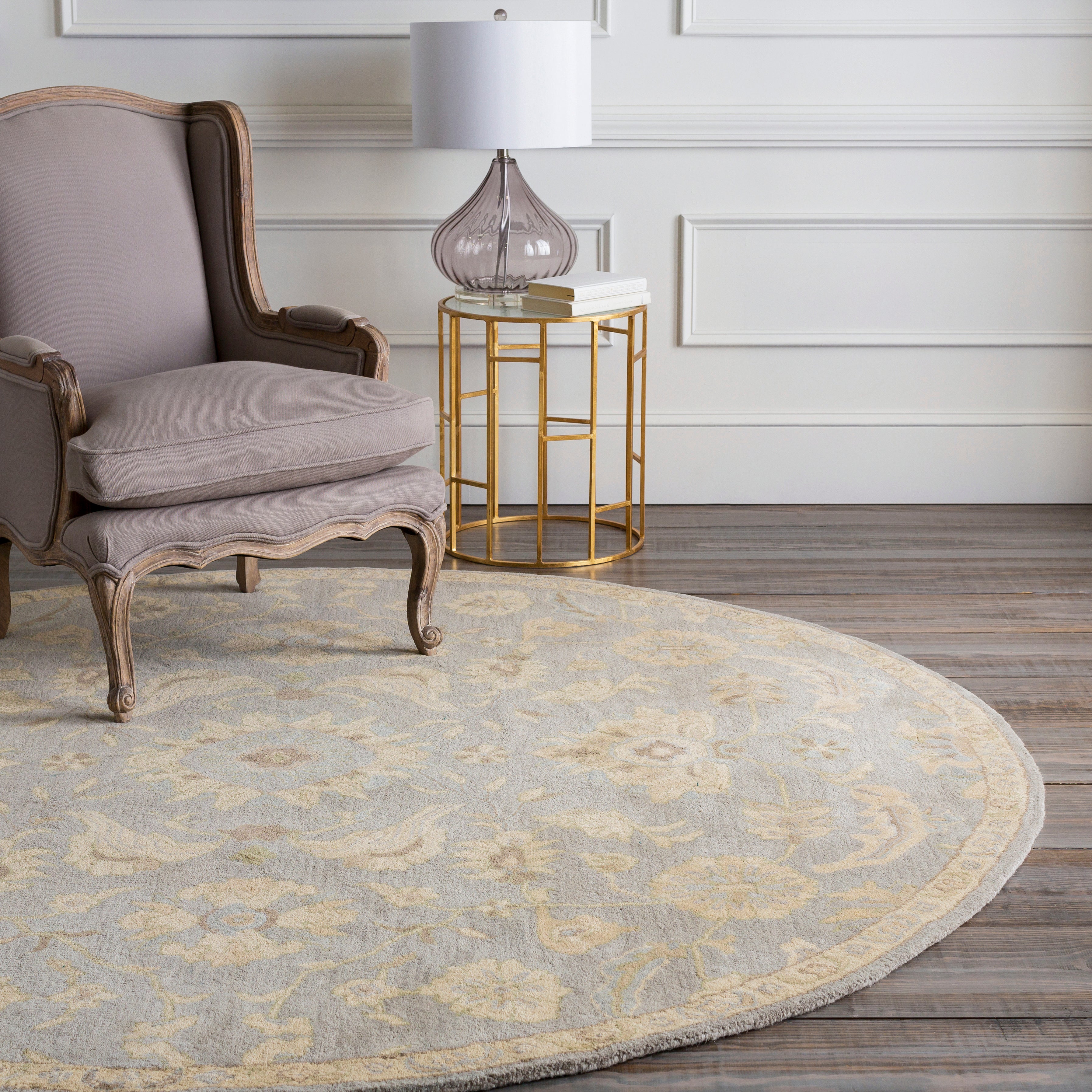 Julian Arctic round wool rug with a light blue and beige floral pattern under an armchair.