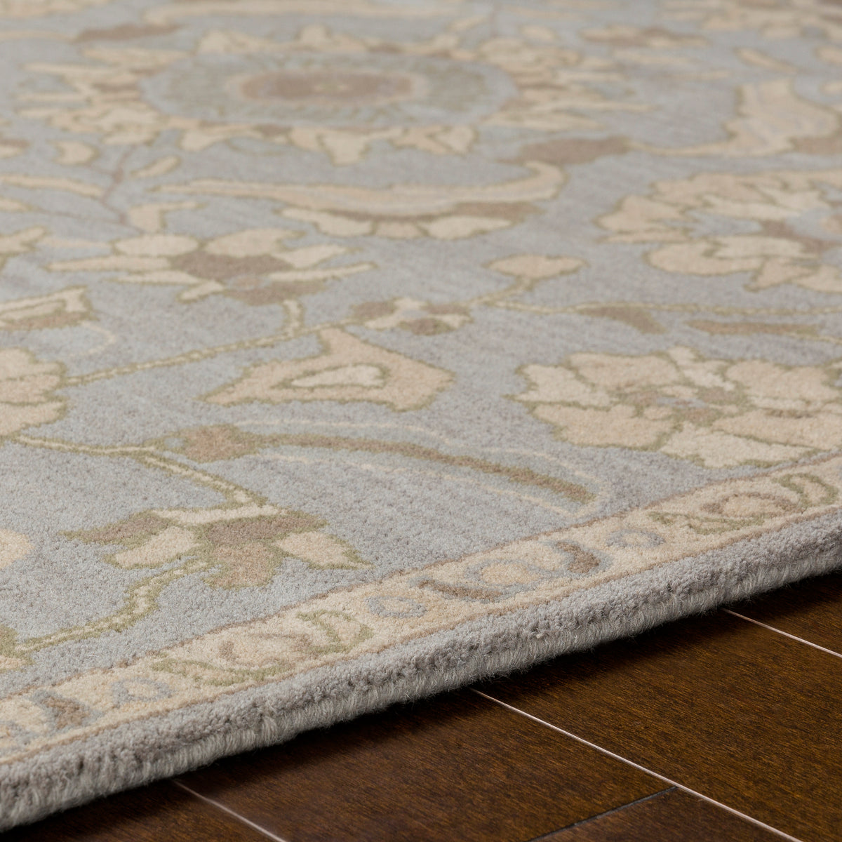 Julian Arctic hand-tufted wool rug with blue and beige floral patterns on wood flooring.