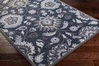 Mediterranean Ocean hand-tufted wool rug with charcoal, slate, and denim floral patterns on dark wood floor.