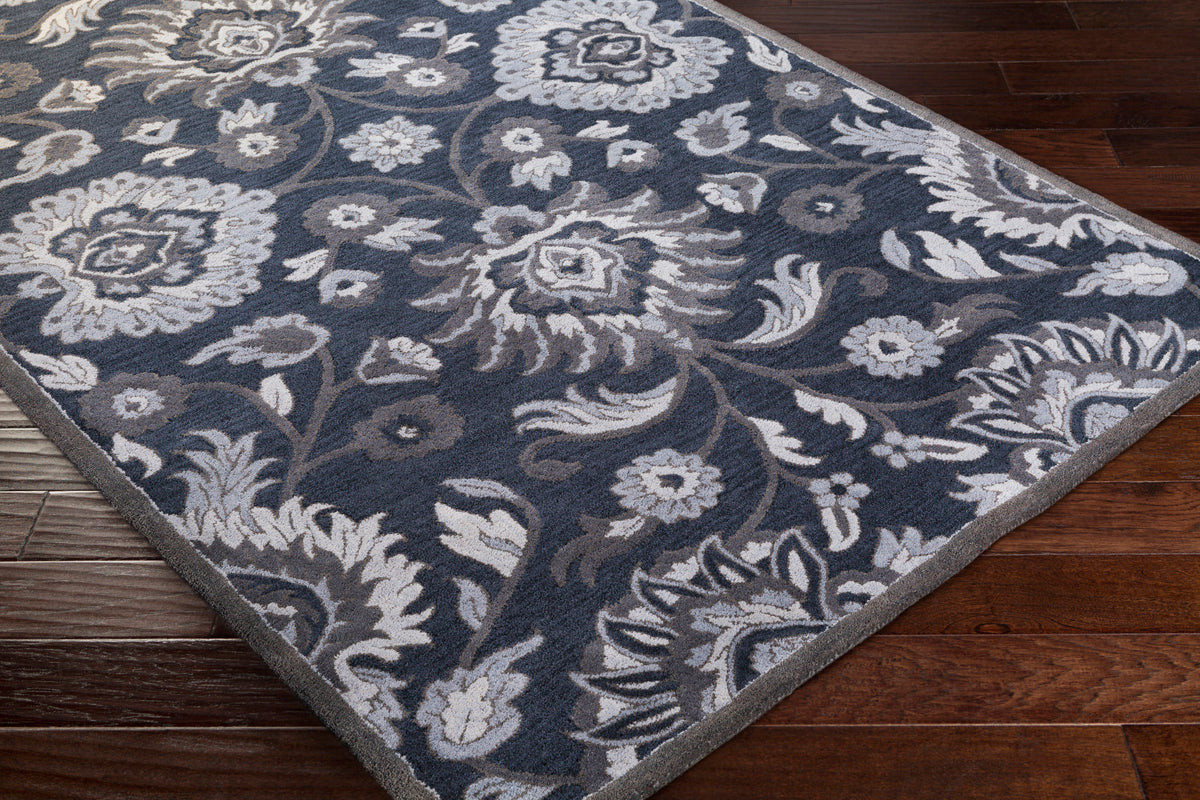 Mediterranean Ocean hand-tufted wool rug with charcoal, slate, and denim floral patterns on dark wood floor.